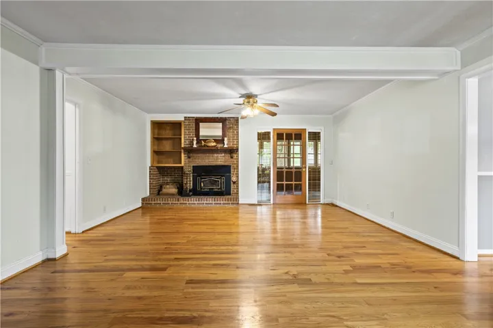 This inviting living room showcases rich hardwood floors and a cozy brick fireplace.
