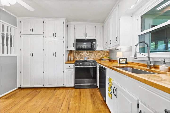 This charming kitchen features abundant white cabinetry, warm wood countertops, and sleek stainless steel appliances.