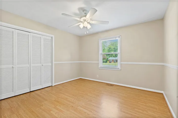 This spacious bedroom offers ample natural light and durable flooring, creating a comfortable living space.