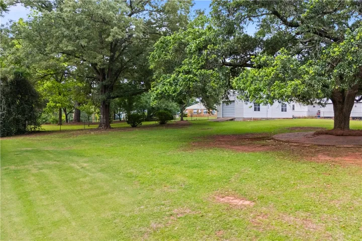 Expansive green lawn and mature trees provide a serene outdoor setting.