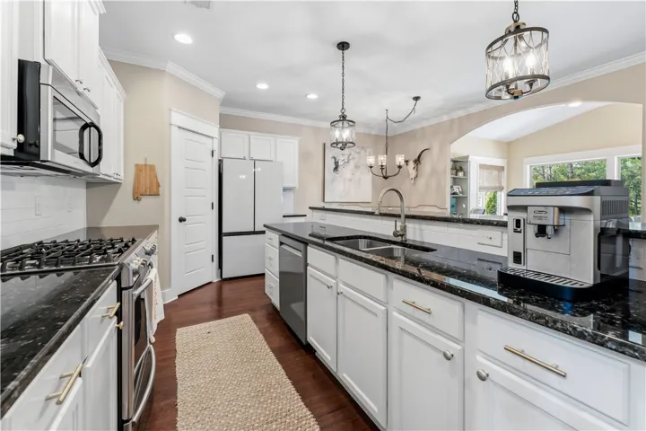 This kitchen features a gas range, microwave, and refrigerator, complemented by granite counters and a kitchen island.