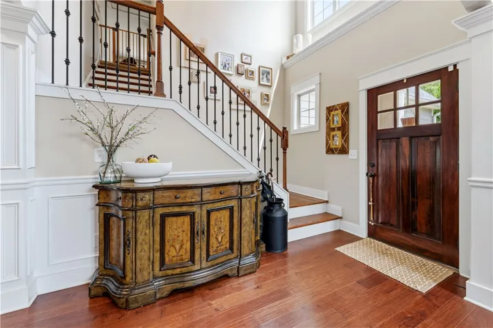 This entry welcomes with warm wood flooring, a striking staircase, and ample natural light.