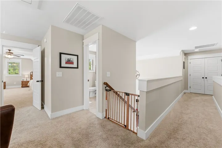 This spacious hallway features soft carpeting and ample natural light, connecting to inviting living spaces.