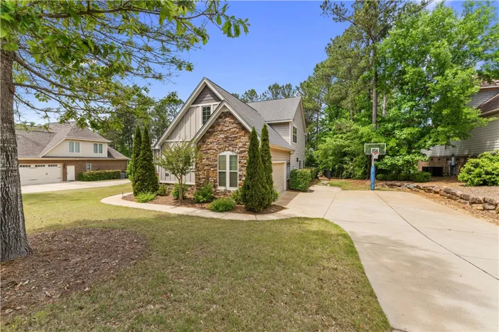 This charming home features a lovely stone facade and an inviting driveway, surrounded by lush greenery.