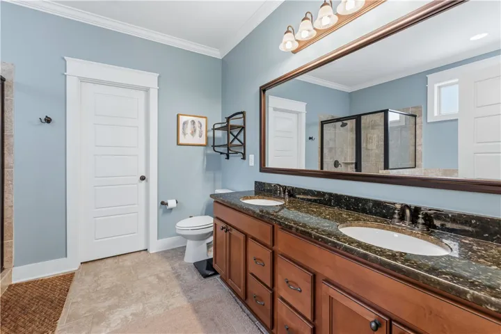 This primary bathroom features a dual vanity, a spacious shower, and elegant tile flooring.