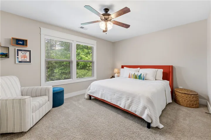 This cozy bedroom offers comfort and a tranquil view of lush greenery through its large windows.