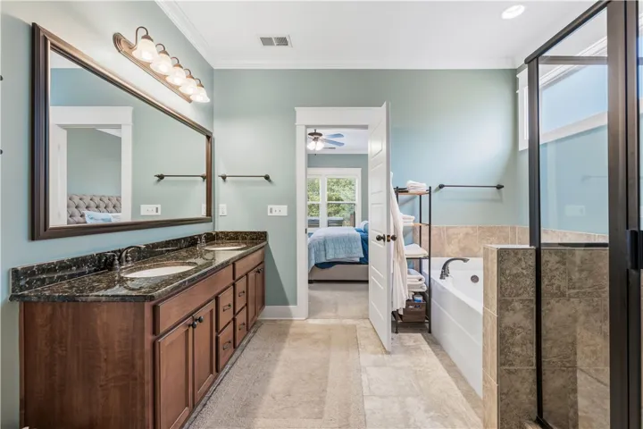 This serene primary bathroom offers dual sinks, a luxurious soaking tub, and a separate shower.