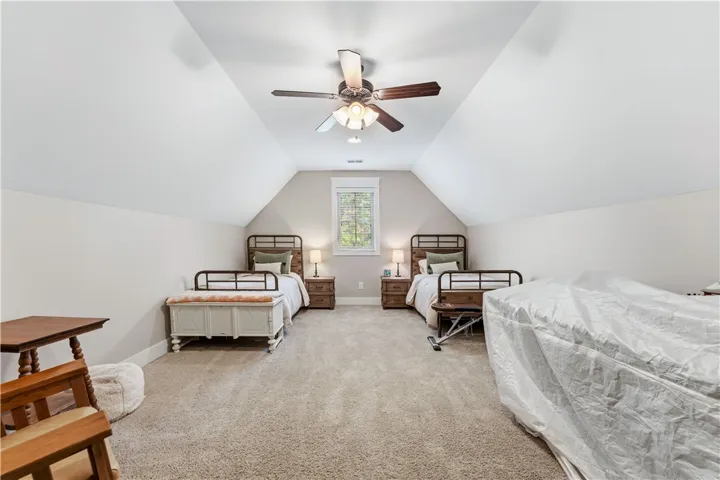 This spacious bedroom features ample room with comfortable carpeted flooring and vaulted ceilings.