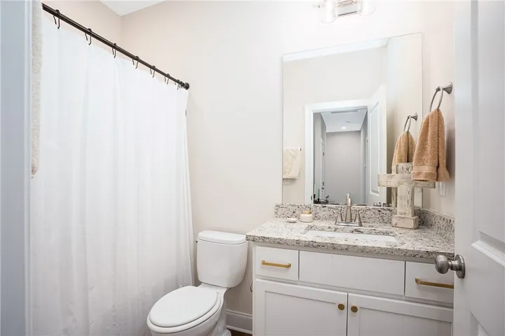 This bright bathroom features a spacious vanity with elegant granite counters and a clean, crisp aesthetic.