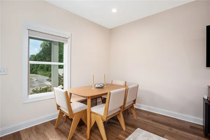 This bright dining area features a large window, recessed lighting, and elegant wood flooring.