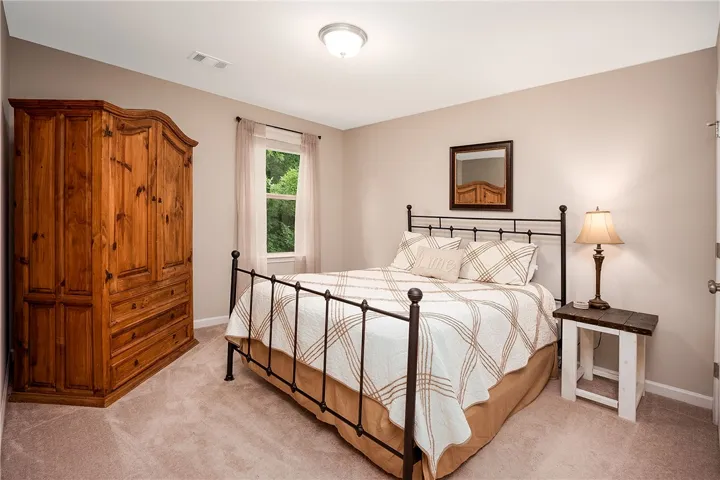 This cozy bedroom features plush carpeting and a large window, creating a serene and comfortable retreat.