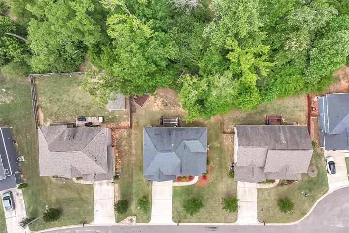 This aerial view showcases a residential property nestled among lush trees with ample outdoor space.