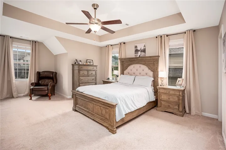 This primary bedroom features plush carpeting and a sophisticated tray ceiling, creating a serene retreat.