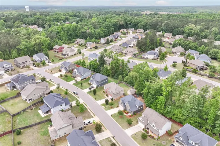 An aerial view captures a serene residential neighborhood surrounded by lush greenery and mature trees.