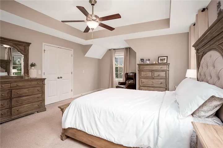 This spacious primary bedroom features a ceiling fan, plush carpet, and ample natural light.