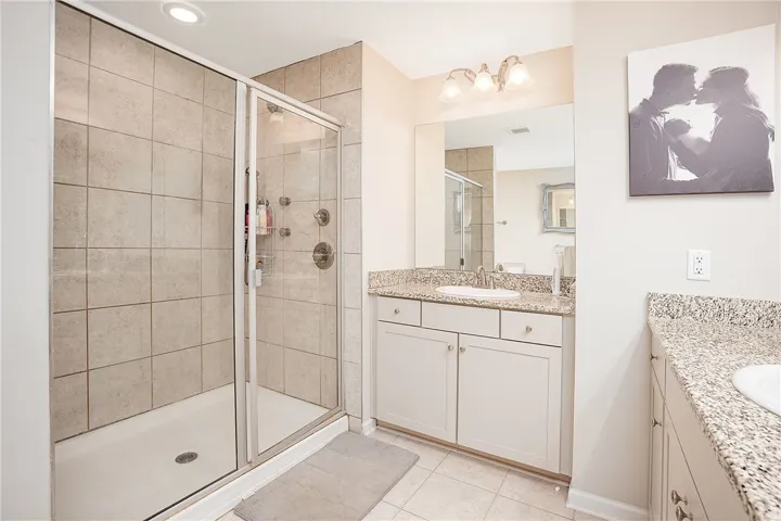 This bathroom features granite countertops, a tiled shower, and a vanity with ample storage.
