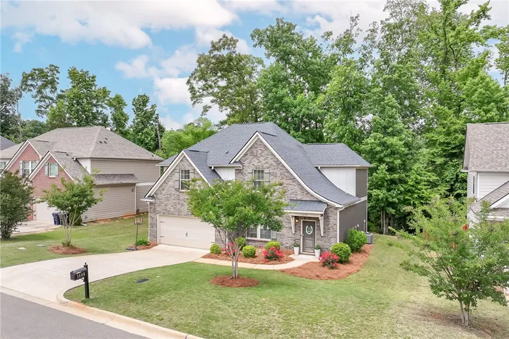 This charming home offers a brick and siding exterior with an inviting front entrance and lush landscaping.