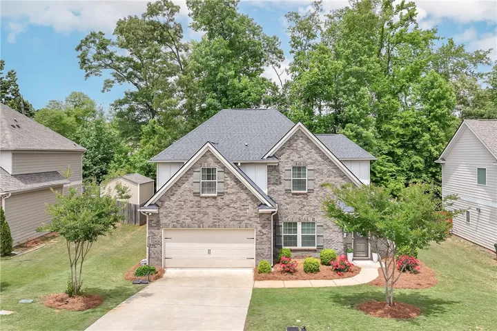 This charming residence features an attached garage and a well-maintained lawn with mature trees.