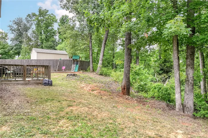 This spacious yard features a versatile deck and ample outdoor storage.