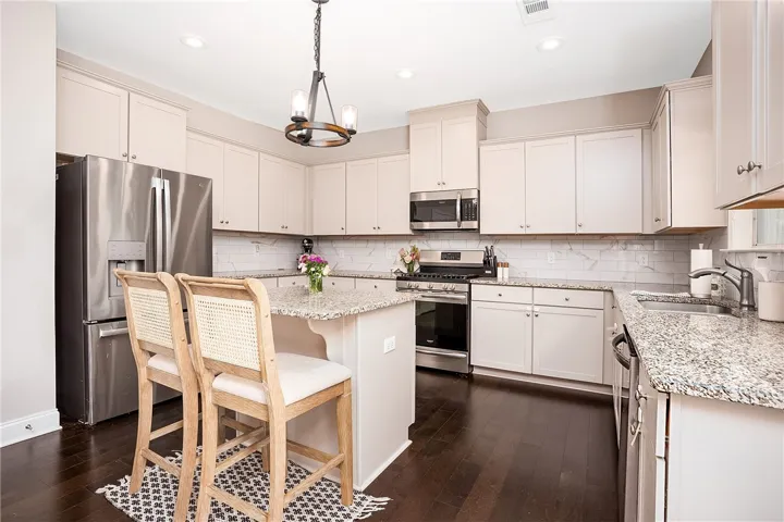 This spacious kitchen offers ample granite counter space, modern appliances, and a convenient island.