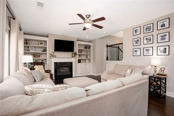 This inviting living space features built-in shelving, a fireplace, and elegant hardwood flooring.