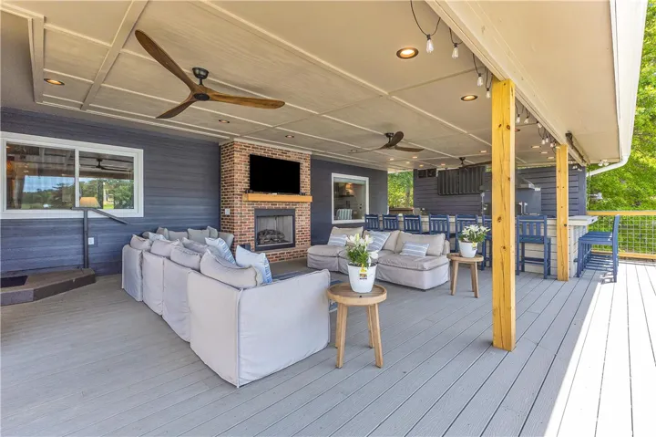 An inviting outdoor patio features a fireplace, ceiling fans, and an outdoor kitchen, perfect for entertaining.