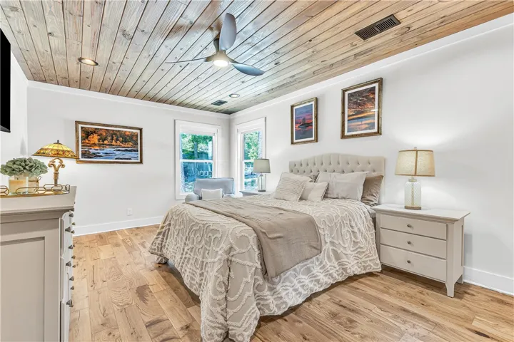 This inviting bedroom features rich hardwood flooring and a stylish ceiling fan, perfect for comfortable living.