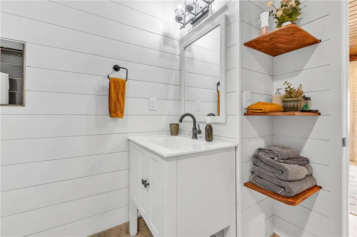 This clean and bright bathroom features a modern vanity and practical corner shelving.