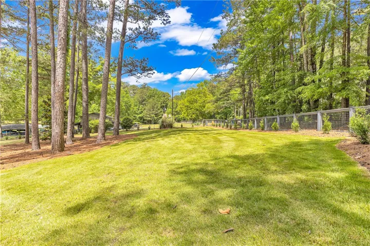 Expansive green lawn framed by mature trees and a sturdy metal fence.