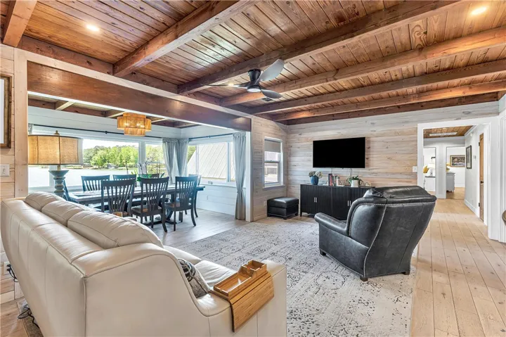 This bright living space features wood beam ceilings and a dining area with scenic waterfront views.