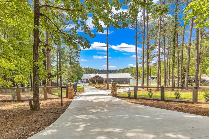 This private estate features a winding driveway leading to a waterfront home surrounded by lush trees.
