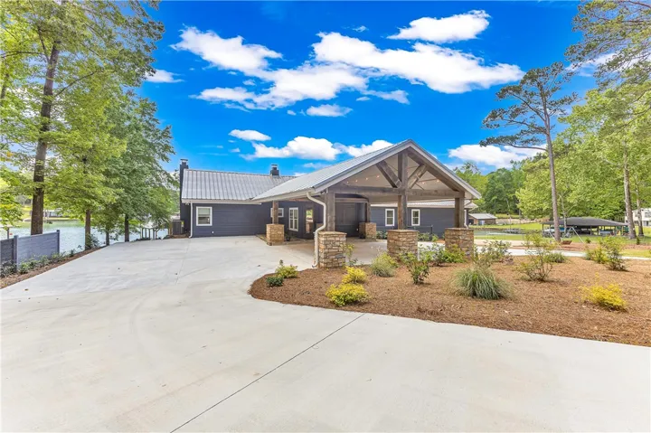 This waterfront property features a spacious driveway and a covered entrance, all set against a serene lake.
