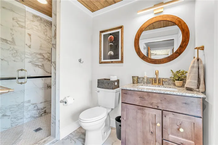 This bathroom features a sleek vanity, elegant granite counters, and a modern walk-in shower.