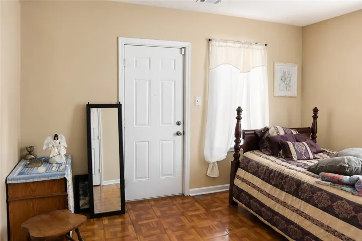 This cozy bedroom features warm wood flooring and ample natural light, creating a comfortable retreat.