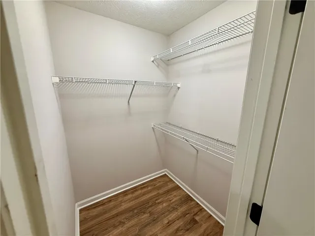 This organized walk-in closet offers practical storage solutions with wire shelving and durable flooring.