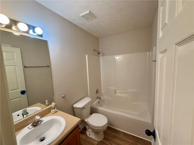 This clean and bright bathroom features a combined shower and tub, offering functional comfort.