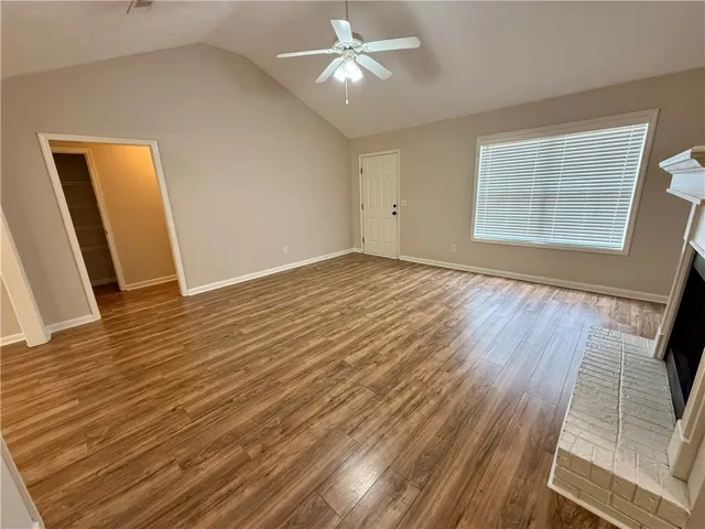 This bright living space features vaulted ceilings and wood flooring, centered around a cozy fireplace.
