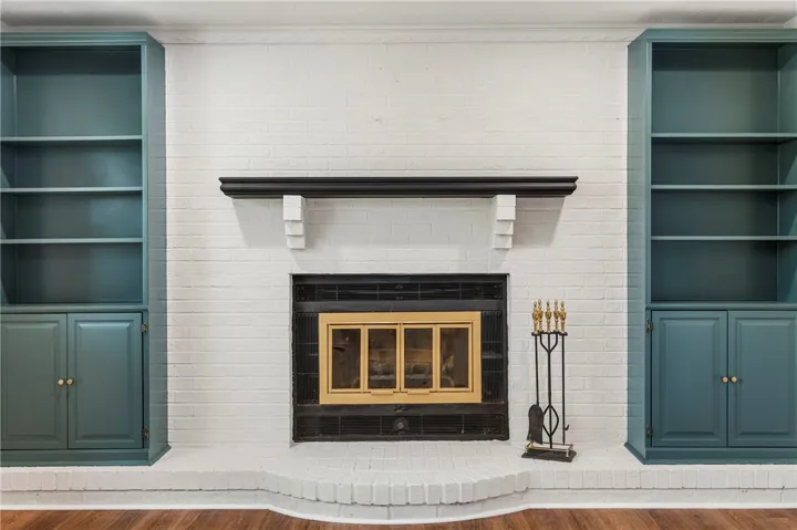 This living area features a classic brick fireplace flanked by built-in shelving, creating a focal point.