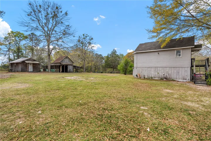 This expansive yard offers ample space with charming rustic structures, perfect for outdoor activities.
