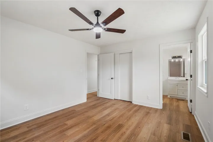 This bright and airy bedroom features beautiful wood flooring and convenient access to an adjacent bathroom.