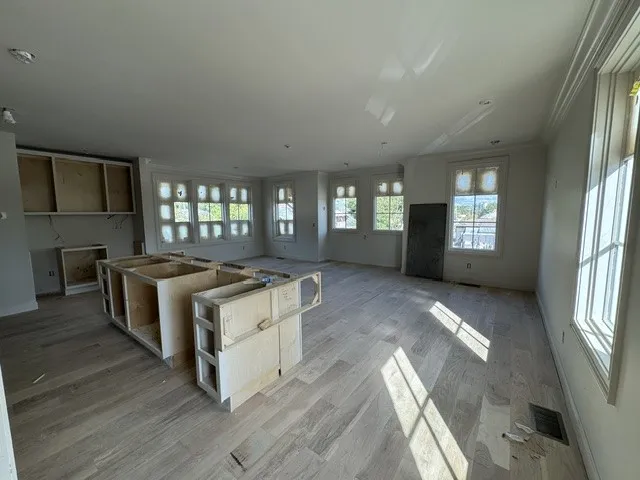 Sunlight streams across the wide-plank wood flooring in this unfinished kitchen and living area.