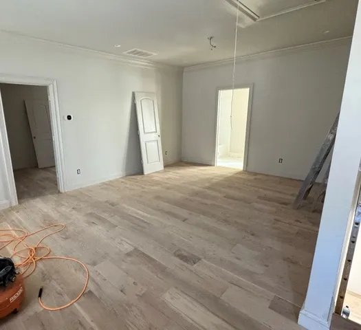 Smooth crown molding and light wood floors bring elegant structure to this spacious room.
