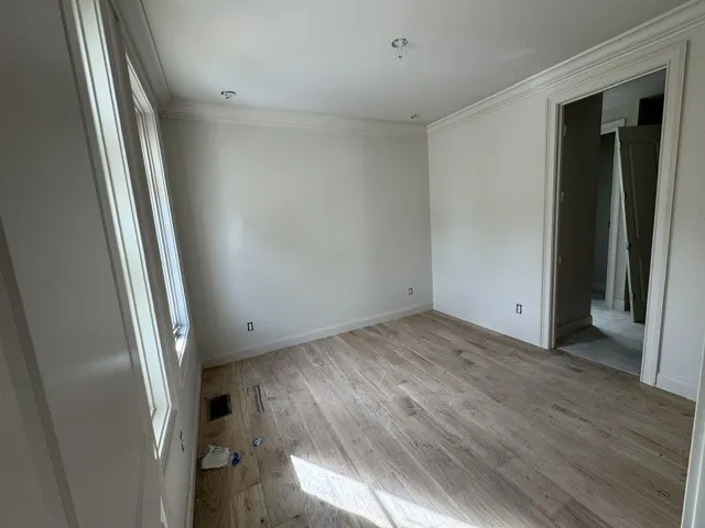 Hardwood floors and elegant crown molding define this versatile, light-filled room.