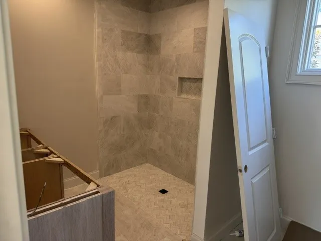 Tiled walk-in shower under construction showcases timeless stone detailing.