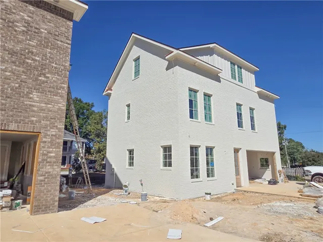A multi-level home under construction displays light brick siding and tall windows.