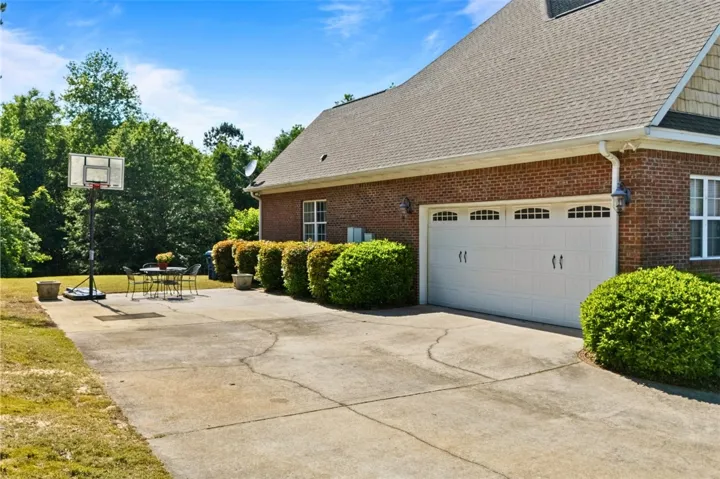The concrete driveway leads to a double garage with additional parking.