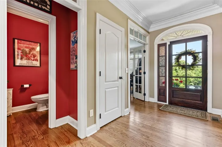 This inviting entryway features rich wood flooring, crown molding, and a beautifully arched front door.