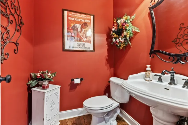 The powder room has rich, warm walls and elegant fixtures.