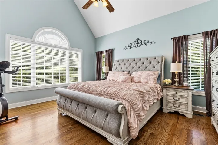 The spacious primary bedroom has vaulted ceilings, rich hardwood flooring and access to the patio/deck.