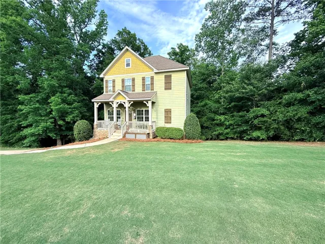 This charming home offers a welcoming facade nestled among lush greenery and a spacious front yard.